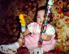 [dressed-up Lyra holding two candy quarterstaffs]